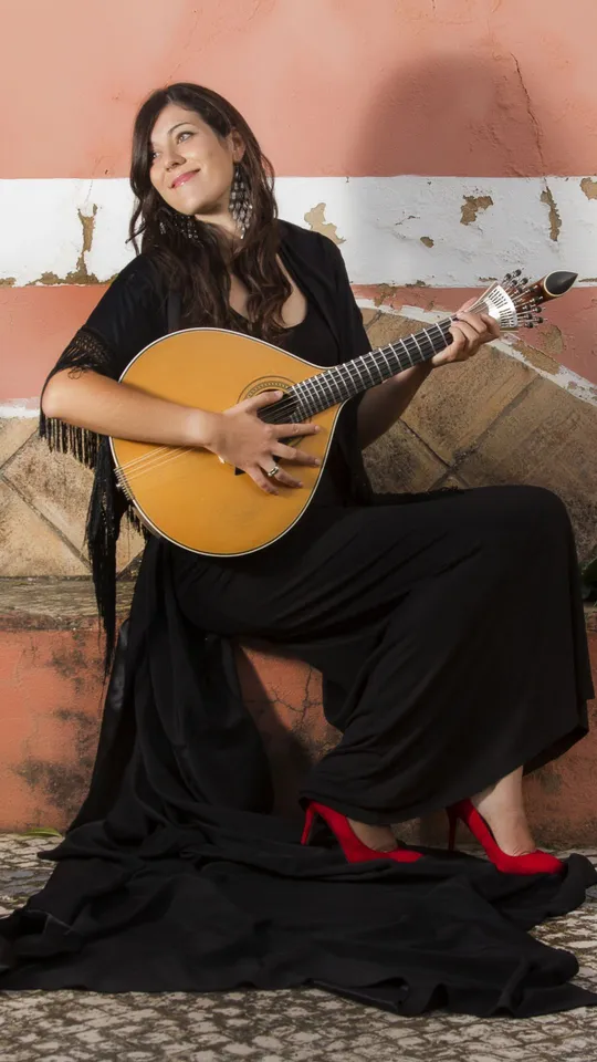 Donna portoghese seduta che suona strumento musicale a corde